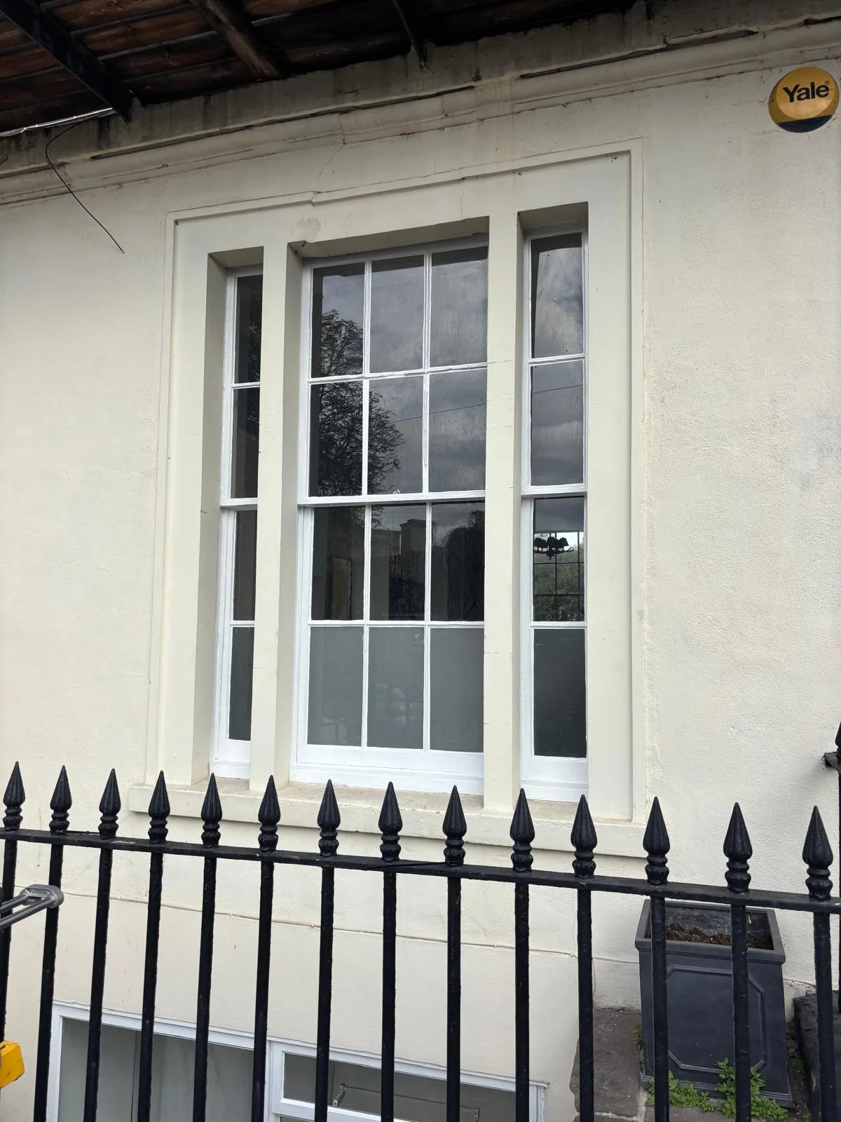 White multi-pane window behind a black iron railing.