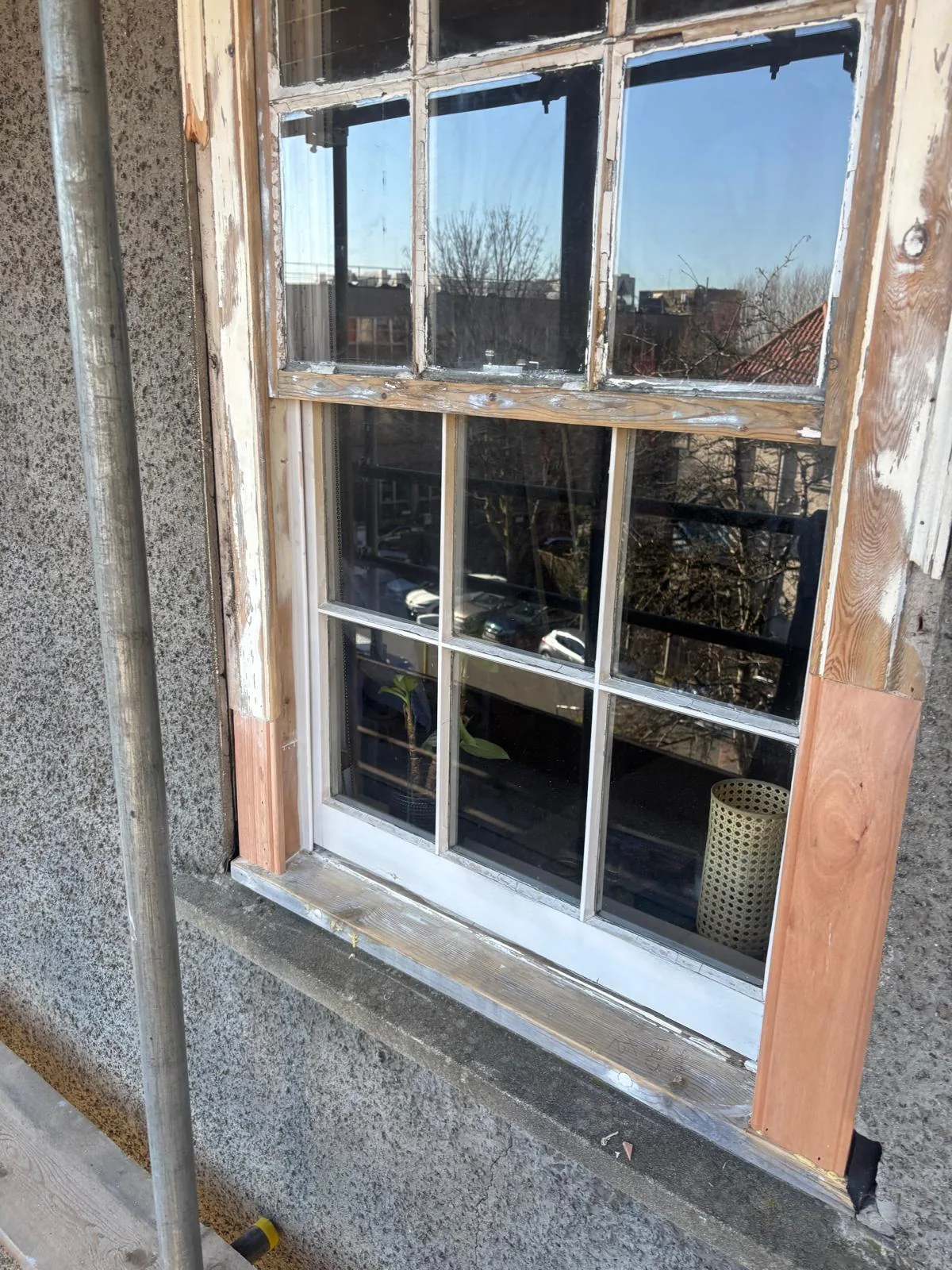 Timber window surround being renewed beside sash window.
